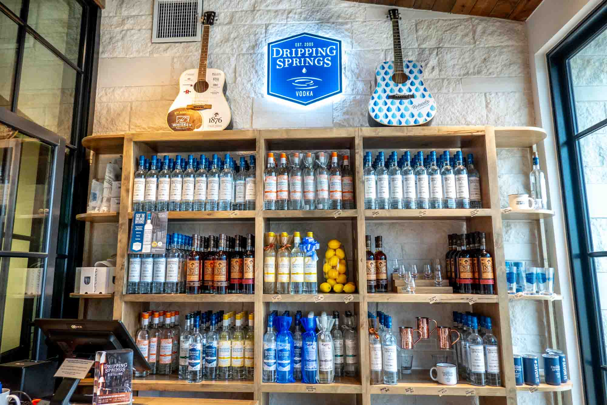 Liquor bottles on shelves under a sign for "Dripping Springs Vodka."