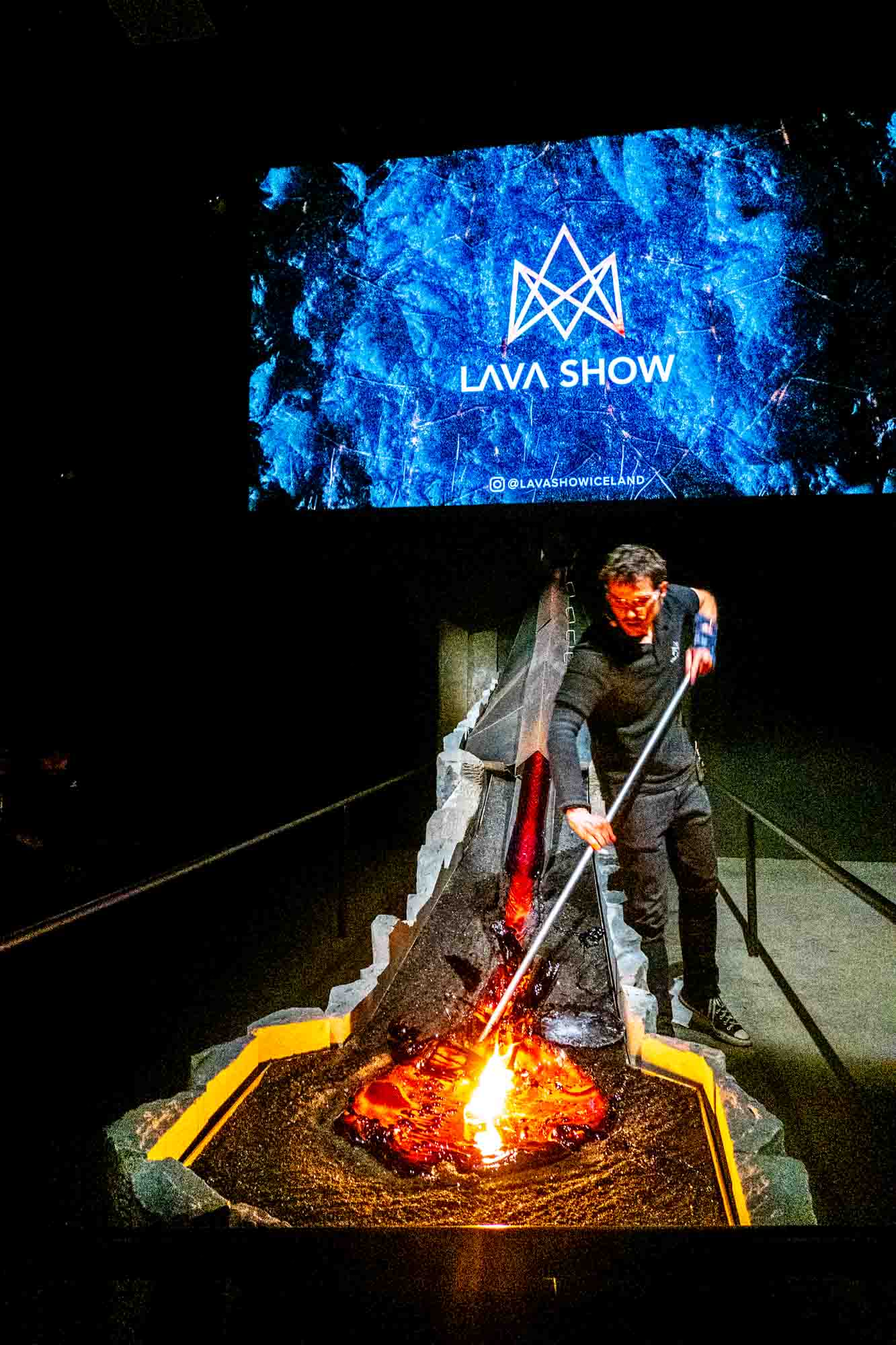 Man conducting demonstration with molten lava in front of a sign for "Lava Show."