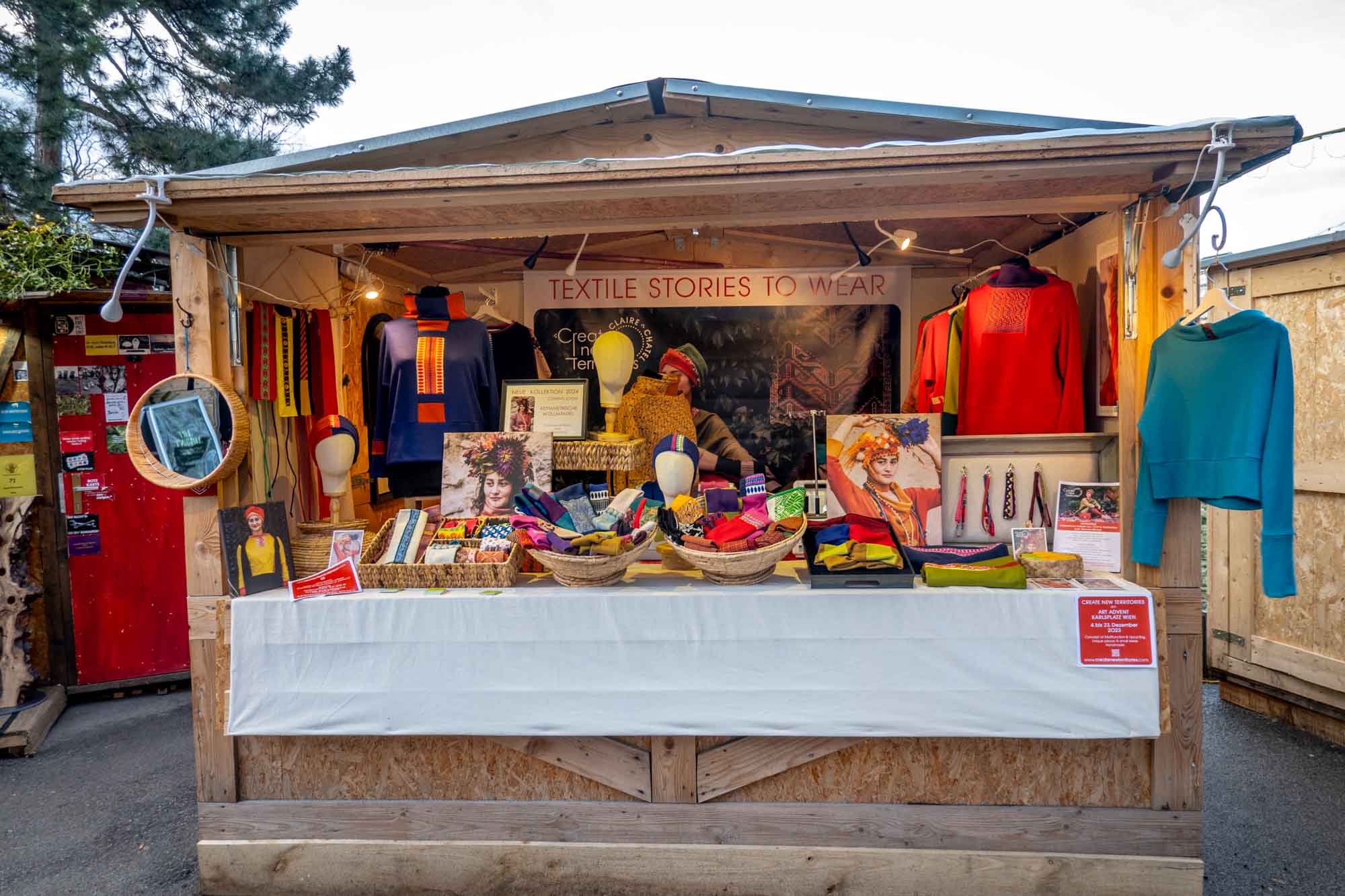 Person selling clothes in a wooden chalet at a Christmas market.