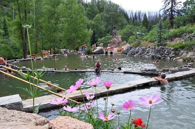 People in the natural pools surrounded by trees and flowers